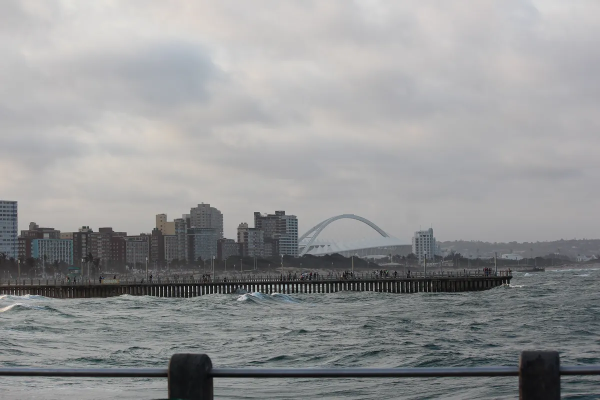 Moses Mabhida Stadium's arch rising behind Durban's beachfront and pier