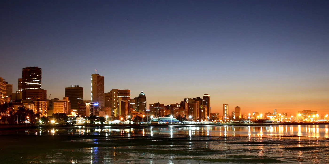 Durban city skyline lit up at dawn, reflected in the harbour water