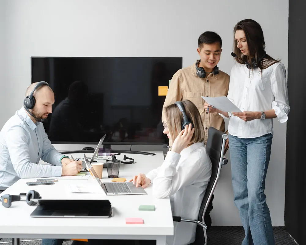Team leader briefing call centre agents wearing headsets at their desks